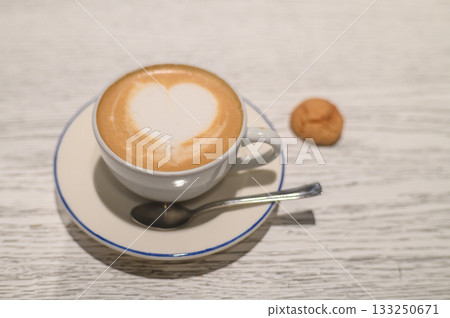 Delightful coffee with heart-shaped froth accompanied by a cookie on a rustic wooden table Delightful coffee with heart-shaped froth accompanied by a cookie on a rustic wooden table 133250671