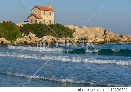 Coastal serenity at a secluded beach house surrounded by gentle waves and rocky landscape. 133250711