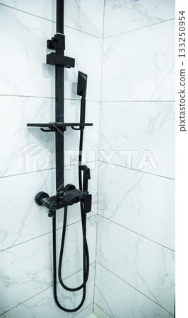 Modern black shower with different spray heads against white tiles in the bathroom, plumbing Modern black shower with different spray heads against white tiles in the bathroom, plumbing 133250954