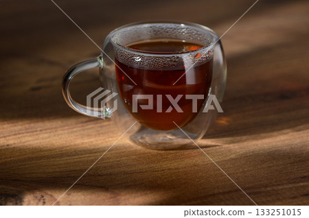 A warm cup of steaming tea resting on a wooden table in soft afternoon light A warm cup of steaming tea resting on a wooden table in soft afternoon light 133251015