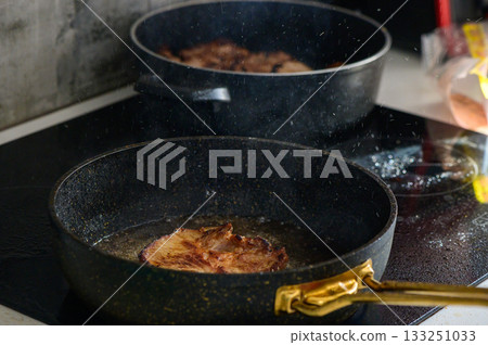 Sizzling pork chops frying in golden oil on a modern stovetop in a cozy kitchen setting at home 133251033