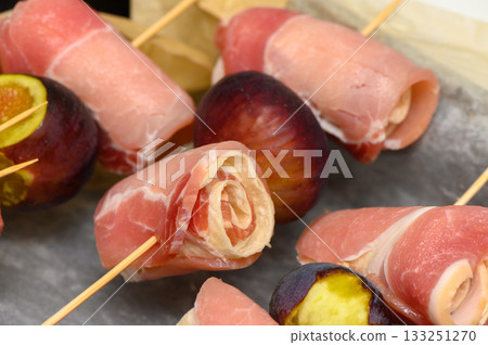 Savory rolls of ham and cheese paired with succulent grilled figs in a gourmet presentation 133251270