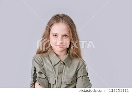 Young caucasian female child with long hair in green shirt smiling in studio 133251311