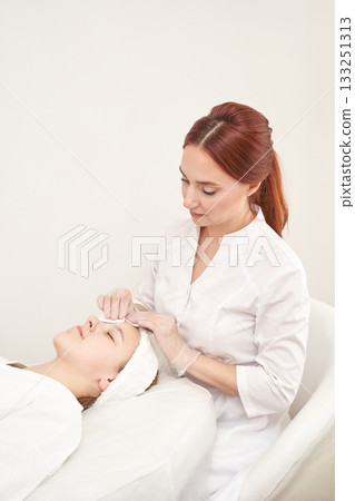 Caucasian female beautician performing facial treatment on young woman in spa Caucasian female beautician performing facial treatment on young woman in spa 133251313