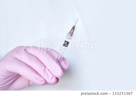 close up of hand in pink medical glove holding syringe with needle against white close up of hand in pink medical glove holding syringe with needle against white 133251367