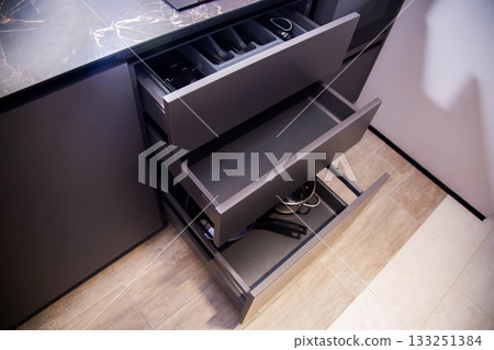 Gray drawers in a custom built-in kitchen. Modern fittings and furniture in the kitchen, close-up Gray drawers in a custom built-in kitchen. Modern fittings and furniture in the kitchen, close-up 133251384