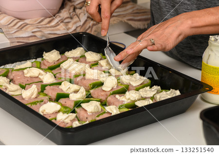 Delicious preparation of savory stuffed peppers with creamy topping in a kitchen setting 133251540