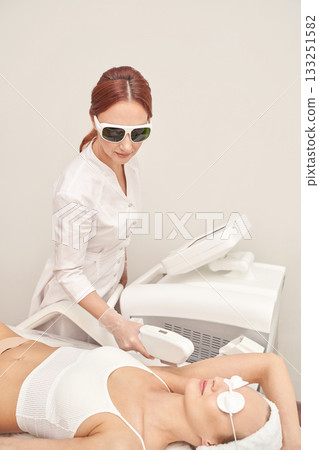 Female caucasian adult receiving laser hair removal treatment at spa by female Female caucasian adult receiving laser hair removal treatment at spa by female 133251582