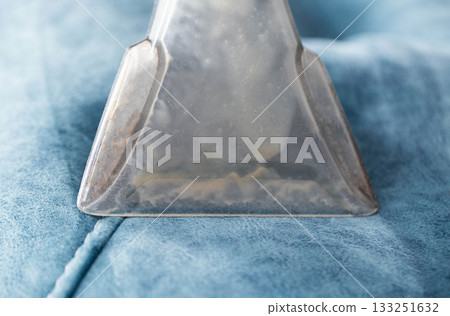 Cleaning process for upholstery with a vacuum tool, showing detail of the suction head in action on a soft surface Cleaning process for upholstery with a vacuum tool, showing detail of the suction head in action on a soft surface 133251632