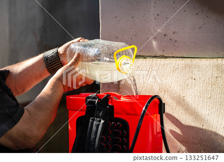 Men's hands pour chemicals into a sprayer to kill parasites on plants. Treatment of plants from diseases and pests. Copy space for text, industry Men's hands pour chemicals into a sprayer to kill parasites on plants. Treatment of plants from diseases and pests. Copy space for text, industry 133251647