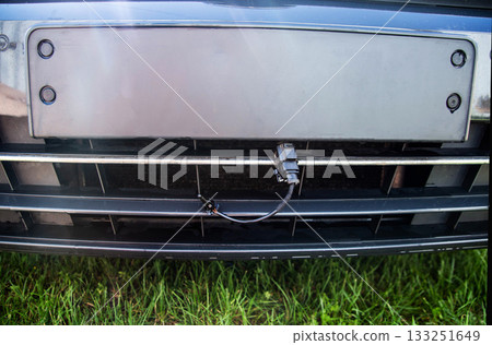 Black car outside air temperature sensor against the background of a car bumper grille. Measuring air temperature, close-up 133251649