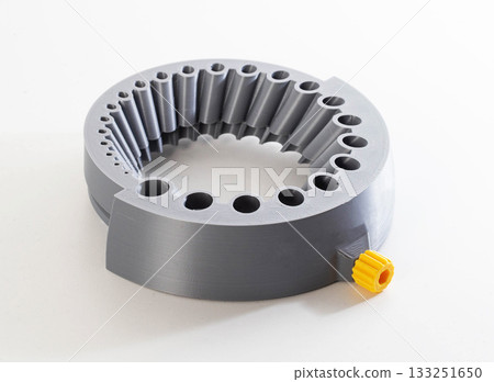 A gray round tool with holes of different sizes for sharpening drills through a grinder, close-up 133251650