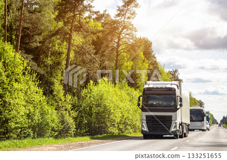 A column of trucks with semi-trailers transports cargo along a country road. Logistics company for the delivery of consolidated cargo. GPS tracking and cargo insurance. Summer nature and forest. Copy A column of trucks with semi-trailers transports cargo along a country road. Logistics company for the delivery of consolidated cargo. GPS tracking and cargo insurance. Summer nature and forest. Copy 133251655