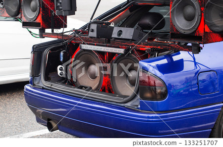 Open Trunk Of Blue Car Displays Huge Custom Audio System. Competition Vehicle Is Equipped With Large Subwoofers. Open Trunk Of Blue Car Displays Huge Custom Audio System. Competition Vehicle Is Equipped With Large Subwoofers. 133251707