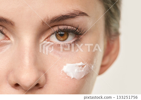 Female caucasian young applying moisturizer cream to face for skincare Female caucasian young applying moisturizer cream to face for skincare 133251756