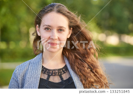 Young caucasian female with long brown hair smiling outdoors in natural setting Young caucasian female with long brown hair smiling outdoors in natural setting 133251845