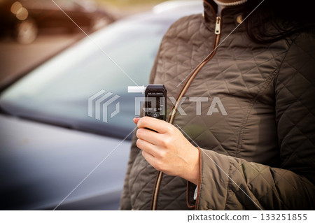 Woman Holding Digital Breathalyzer Before Driving. Responsible Driver Checks Alcohol Level. Copy space for text. Driving license revocation for alcohol Woman Holding Digital Breathalyzer Before Driving. Responsible Driver Checks Alcohol Level. Copy space for text. Driving license revocation for alcohol 133251855
