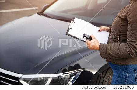 Female Stands By Automobile With Alcohol Tester And Clipboard. Preparing To Document Sobriety Check Results. Female Stands By Automobile With Alcohol Tester And Clipboard. Preparing To Document Sobriety Check Results. 133251860