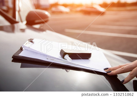 Female Hand Touches Clipboard With Alcohol Tester On Car. Sobriety Check Procedure At Sunset. Female Hand Touches Clipboard With Alcohol Tester On Car. Sobriety Check Procedure At Sunset. 133251862