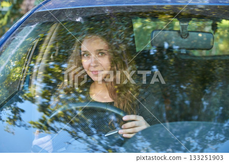 Young caucasian female driving car surrounded by nature reflections through Young caucasian female driving car surrounded by nature reflections through 133251903