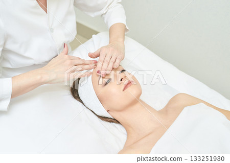 Young caucasian female receiving facial massage in spa for skincare treatment Young caucasian female receiving facial massage in spa for skincare treatment 133251980