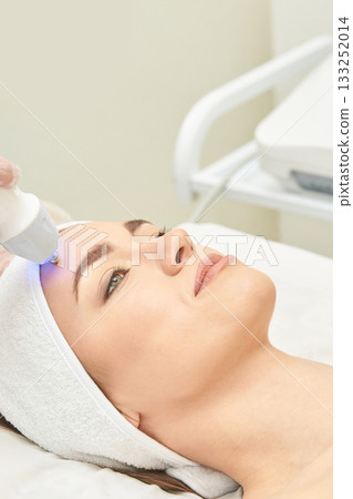 Young caucasian female receiving skincare treatment with laser technology Young caucasian female receiving skincare treatment with laser technology 133252014