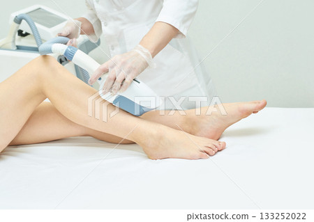 Laser hair removal treatment on female legs by medical professional in clinic Laser hair removal treatment on female legs by medical professional in clinic 133252022