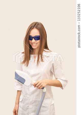 Young caucasian female in white coat holding laser device wearing protective 133252106