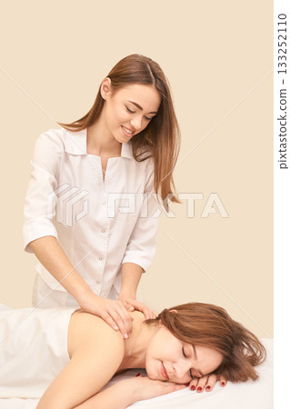 Young caucasian female massage therapist performing relaxation therapy 133252110