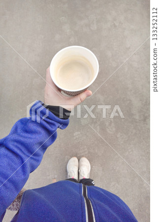 Adult Caucasian female holding a takeaway cup of hot coffee during a walk, first person point of view showing casual sportswear 133252112