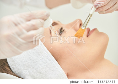 Caucasian female receiving facial treatment with serum and brush in spa Caucasian female receiving facial treatment with serum and brush in spa 133252211