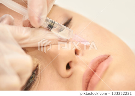 Close-up of young caucasian female receiving cosmetic facial procedure Close-up of young caucasian female receiving cosmetic facial procedure 133252221