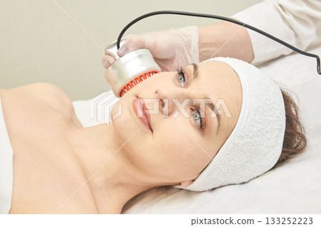 Female caucasian adult receiving facial beauty treatment with handheld device Female caucasian adult receiving facial beauty treatment with handheld device 133252223