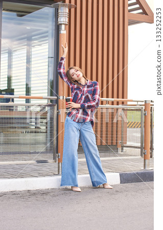 Caucasian female young adult posing in casual plaid shirt and jeans outdoors Caucasian female young adult posing in casual plaid shirt and jeans outdoors 133252253