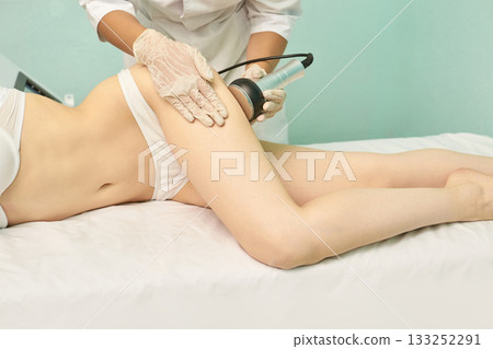 Female adult undergoing leg contouring treatment in spa clinic setting Female adult undergoing leg contouring treatment in spa clinic setting 133252291