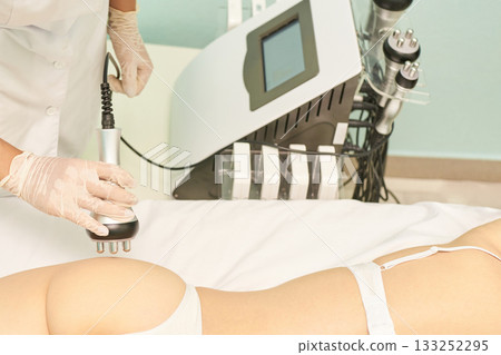 Caucasian female receiving rf cavitation treatment in spa with modern equipment Caucasian female receiving rf cavitation treatment in spa with modern equipment 133252295
