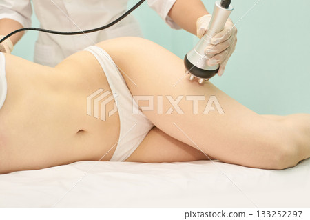 Female receiving non-invasive body contouring treatment in clinical setting Female receiving non-invasive body contouring treatment in clinical setting 133252297