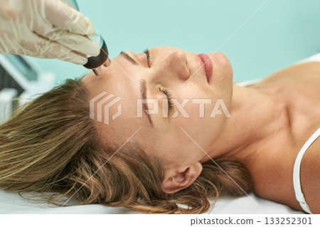 Caucasian female receiving facial treatment in spa clinic focused on skin care Caucasian female receiving facial treatment in spa clinic focused on skin care 133252301
