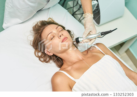 Young caucasian female receiving spa treatment with modern equipment for skin 133252303
