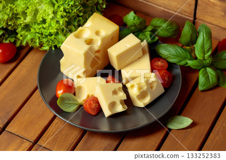 Swiss cheese, green basil, salad, and tomatoes on a wooden table. Swiss cheese, green basil, salad, and tomatoes on a wooden table. 133252383