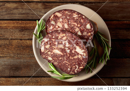 Black pudding or blood sausage accompanied by rosemary. Black pudding or blood sausage accompanied by rosemary. 133252394