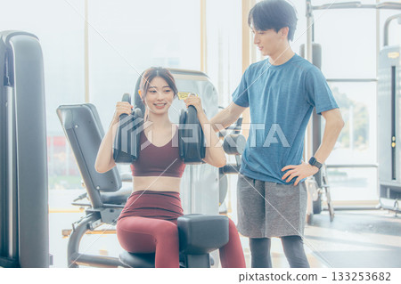 一位女士正在健身房跟隨教練進行肌力訓練。 133253682