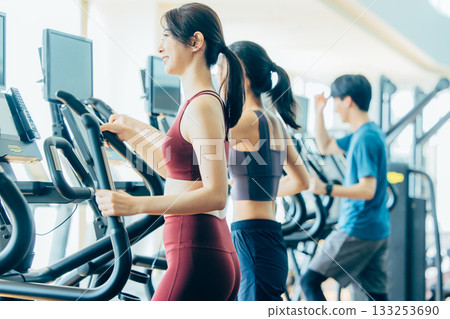 Men and women using cross trainers Men and women using cross trainers 133253690