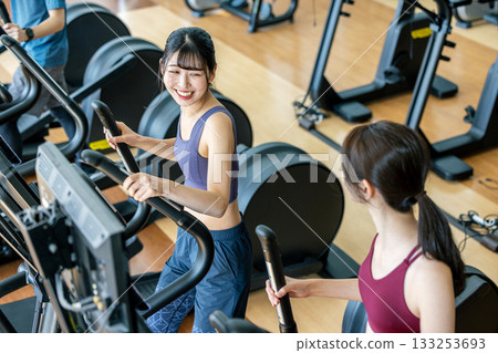Men and women using cross trainers Men and women using cross trainers 133253693
