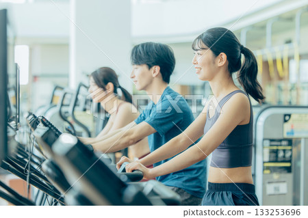 Men and women using upright bikes at the gym 133253696