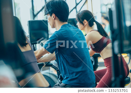 Men and women using upright bikes at the gym 133253701
