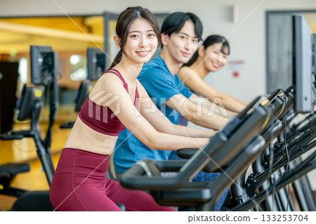 Men and women using upright bikes at the gym 133253704