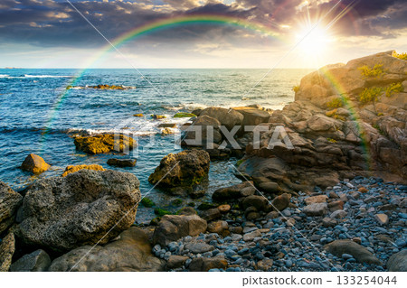 weekend on a rocky beach at the black sea under open blue sky at sunset. beautiful coastline in summer. seascape scenery with clouds above horizon in evening light. sunny weather weekend on a rocky beach at the black sea under open blue sky at sunset. beautiful coastline in summer. seascape scenery with clouds above horizon in evening light. sunny weather 133254044