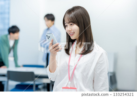 有一部智能手機的女商人在辦公室 有一部智能手機的女商人在辦公室 133254321