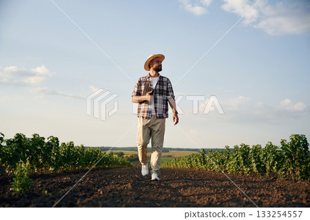 Front view, walking forward. Farmer is on the agricultural field 133254557